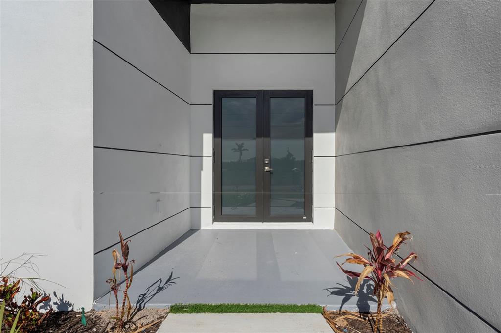 A bright, empty living room features white tile floors, a tray ceiling, and sliding doors — 2725 EMBERS PARKWAY W, CAPE CORAL, FL