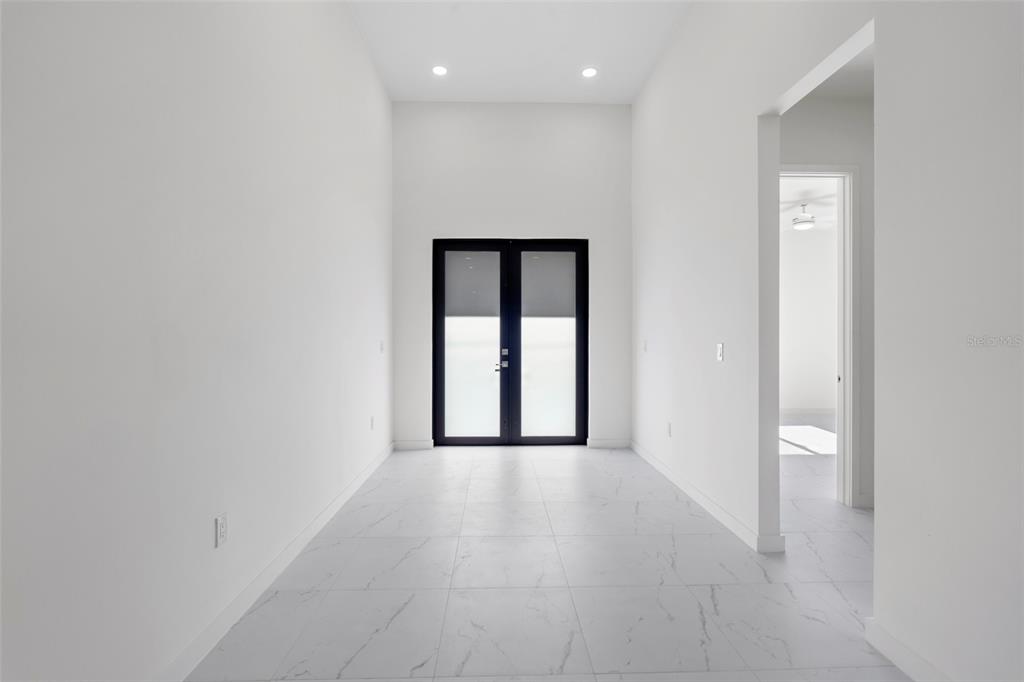 A bright dining room features white walls, glossy tile floors, and a dark wood table — 2725 EMBERS PARKWAY W, CAPE CORAL, FL