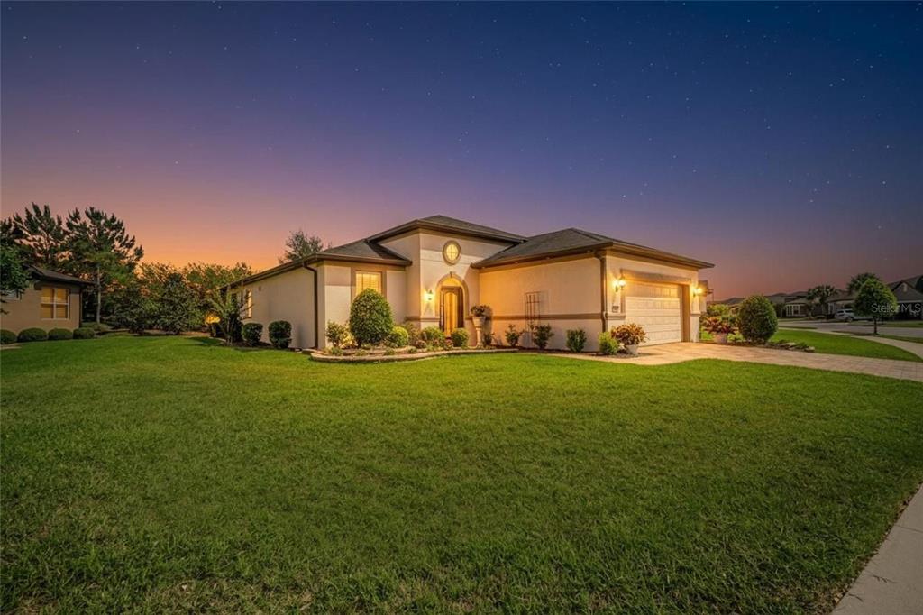 A single-story house with a beige stucco exterior and a two-car garage at dusk — 6707 SW 95TH CIRCLE, OCALA, FL