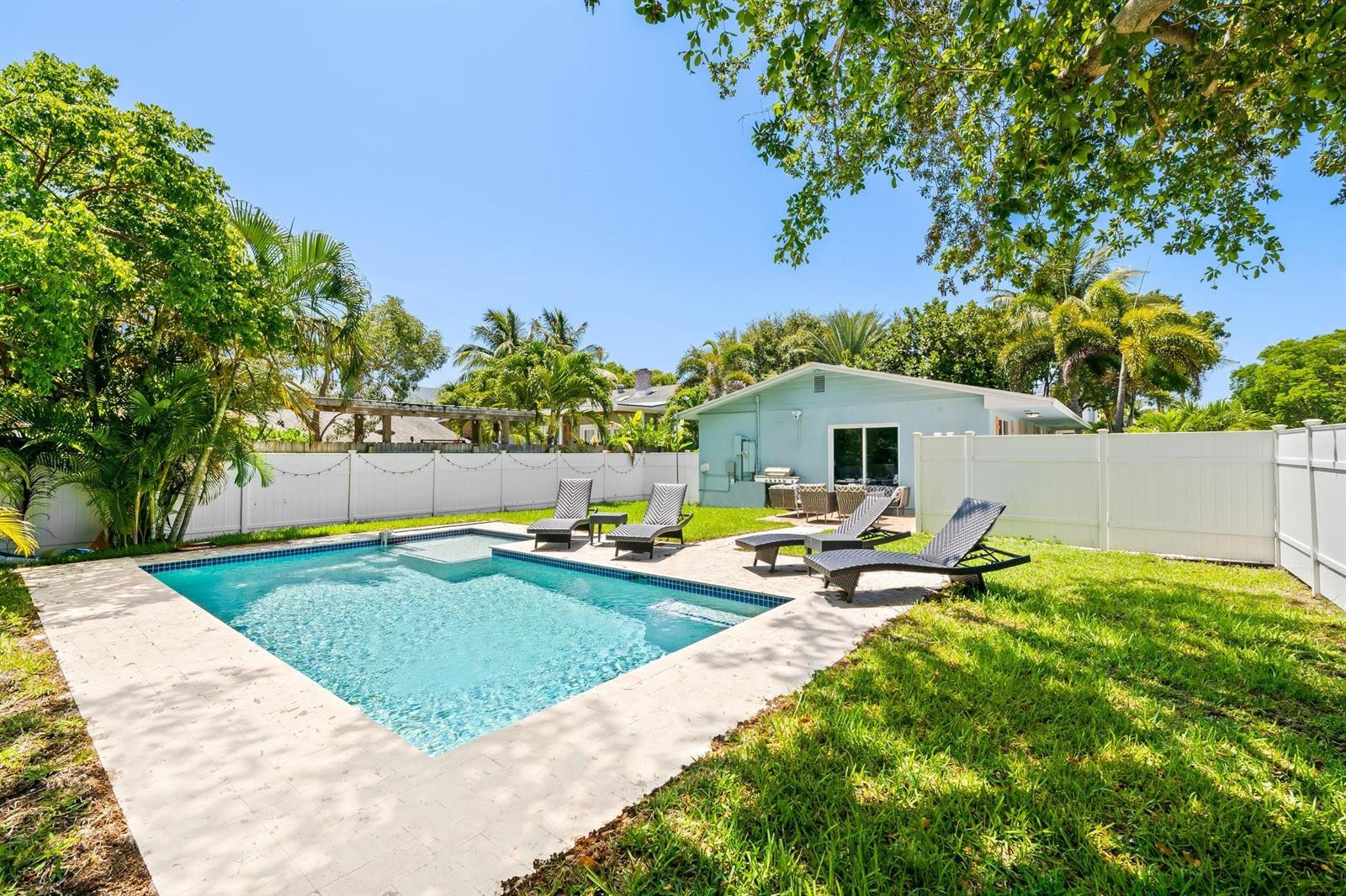 A backyard features a swimming pool, lounge chairs, a lawn, and a light blue house — 415 SE 3rd Avenue, Delray Beach FL 33483, DELRAY BEACH, FL