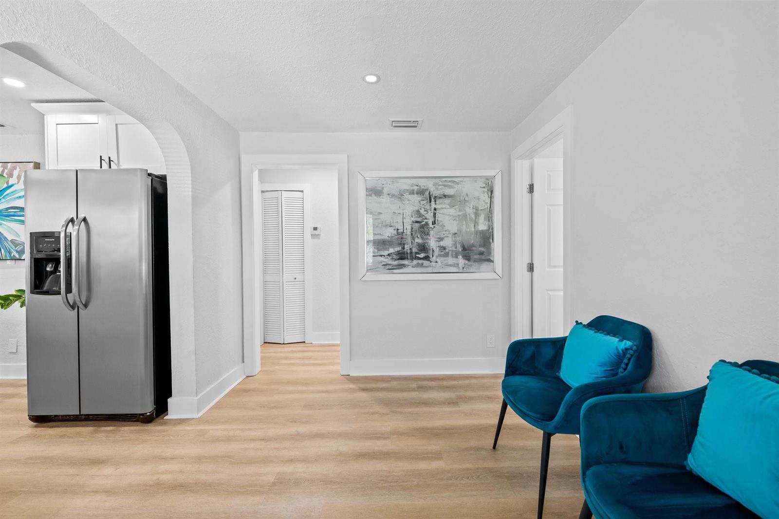 A room with light wood flooring, a stainless steel refrigerator, and two blue velvet chairs — 415 SE 3rd Avenue, Delray Beach FL 33483, DELRAY BEACH, FL