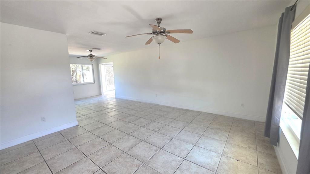 An empty room features light-colored tile flooring, white walls, and two ceiling fans — 4350 MARALDO AVENUE, NORTH PORT, FL
