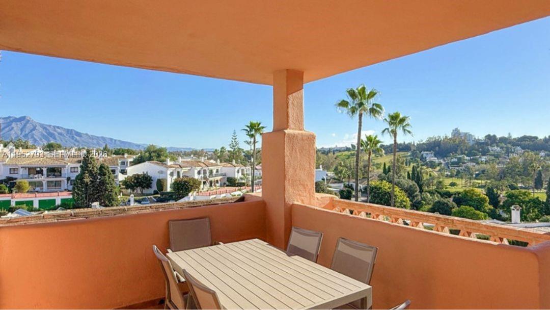 A balcony with a dining table overlooks a residential area with palm trees and mountains — 29679 C. Chopo Marbella-Spain # 7311, FL, FL