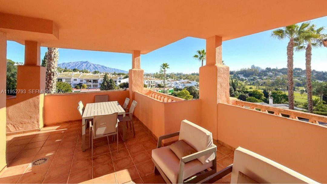 A spacious, terracotta-tiled balcony features outdoor dining furniture and views of distant mountains — 29679 C. Chopo Marbella-Spain # 7311, FL, FL
