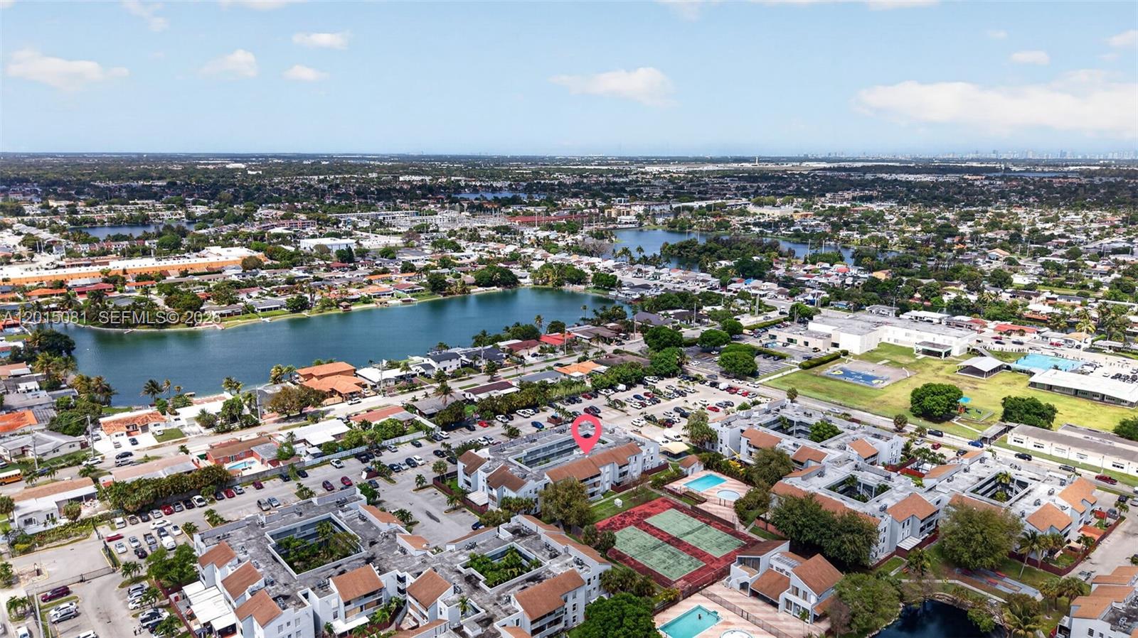 An aerial view shows a multi-story apartment complex with tennis courts and a swimming pool — 1755 W 60th St # D301, Hialeah FL 33012, HIALEAH, FL