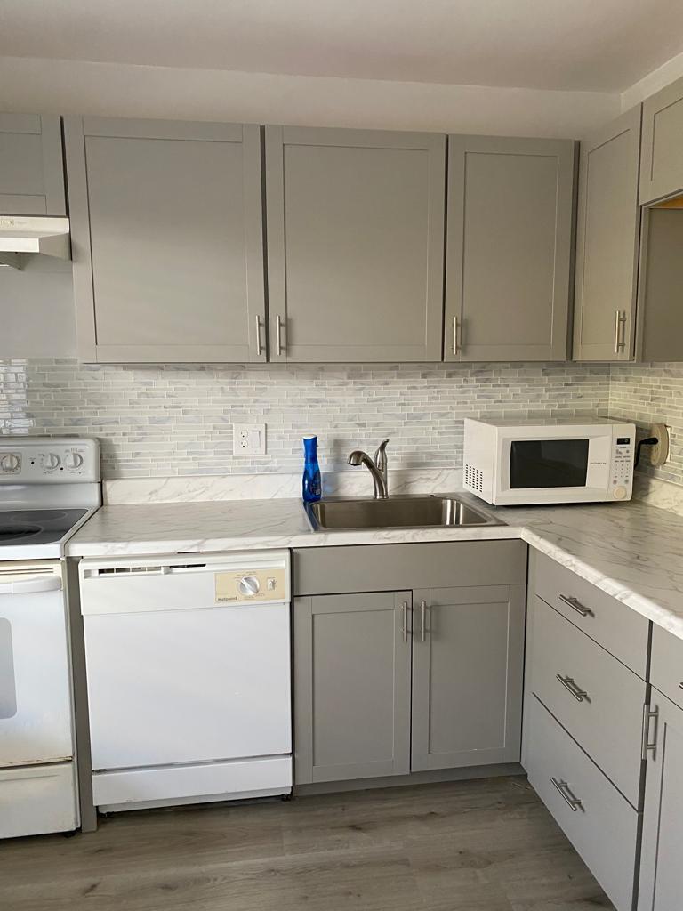 A kitchen featuring grey cabinets, white marble-patterned countertops, a stainless steel sink, and white appliances — 19 Abbey Lane # 206, Delray Beach FL 33446, DELRAY BEACH, FL