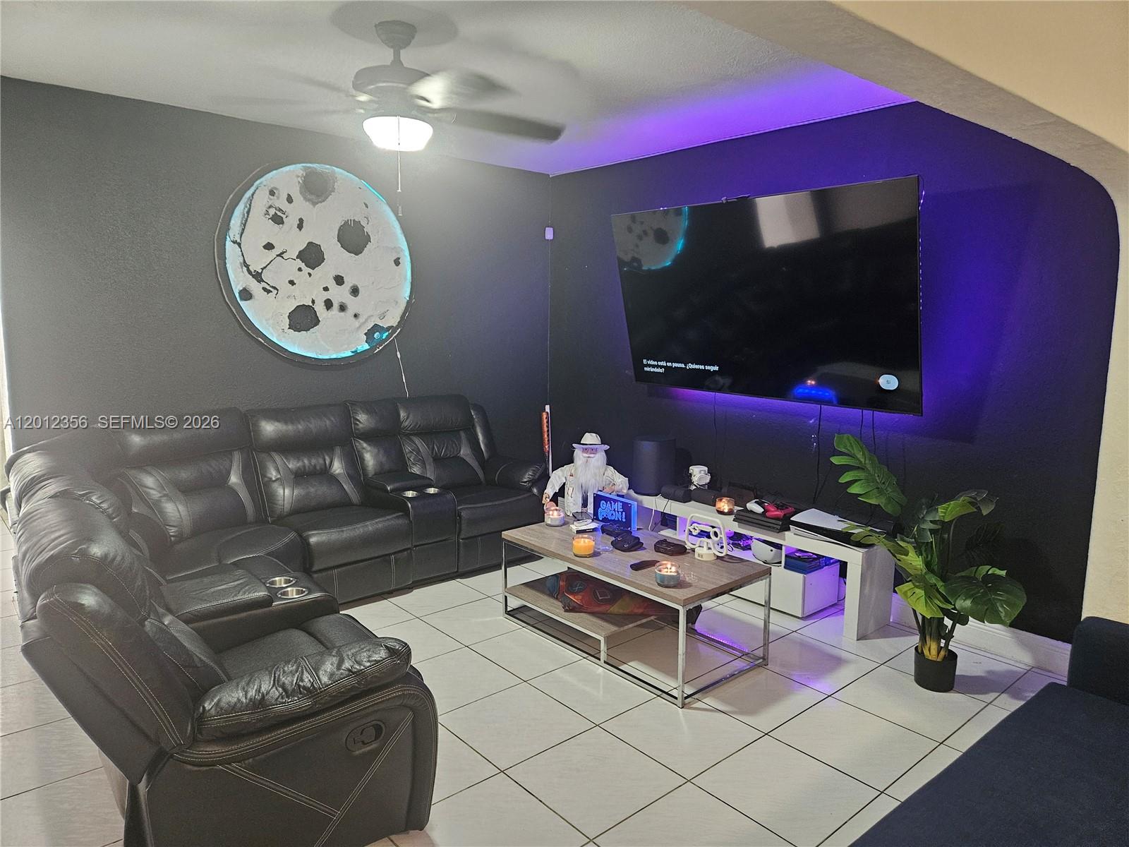 A living room features a black leather sectional, a wall-mounted television, and a circular moon-themed light — 2231 NW 4th Ter, Miami FL 33125, MIAMI, FL