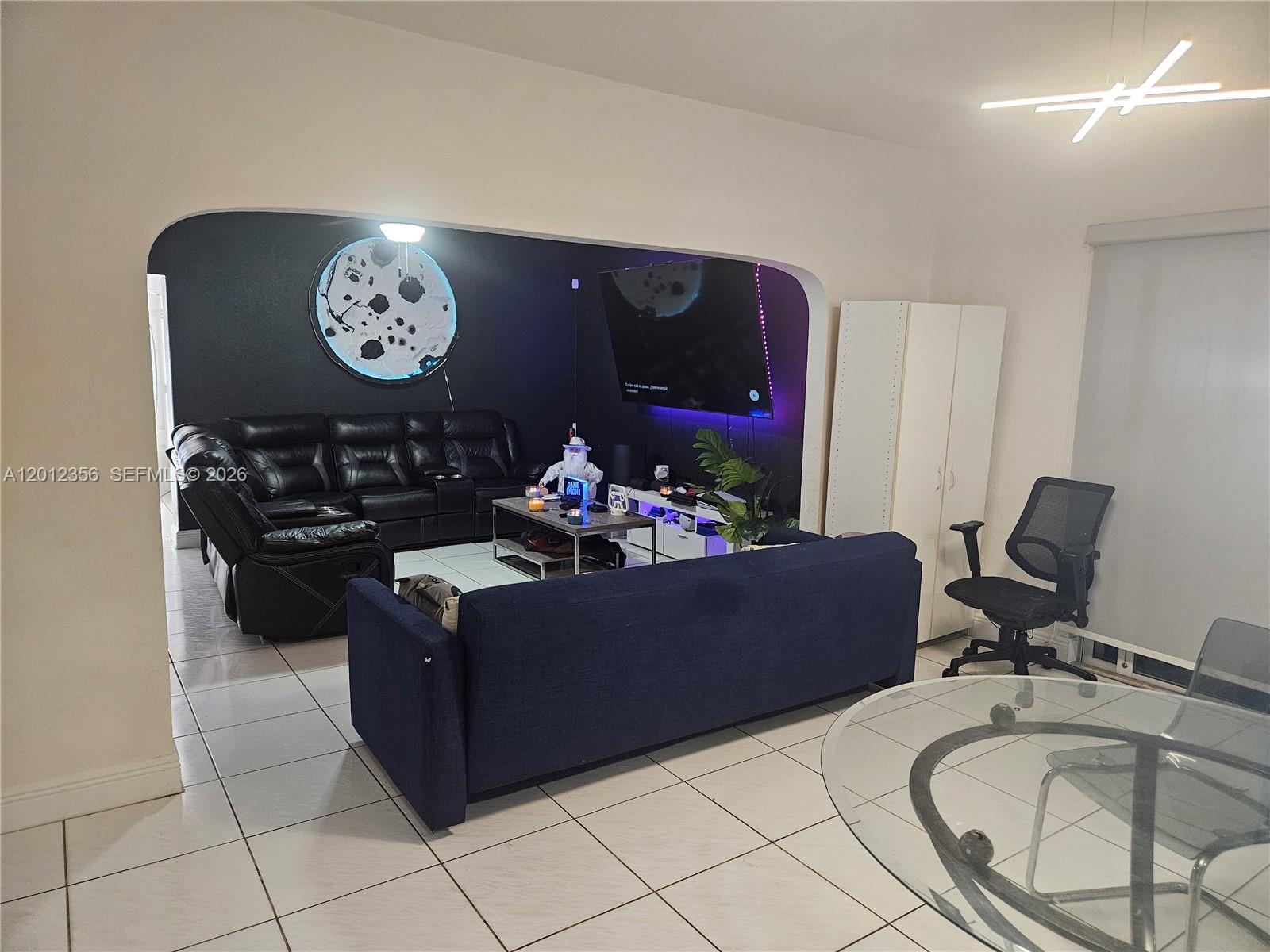 A living room features a dark accent wall, a black leather sofa, and tile flooring — 2231 NW 4th Ter, Miami FL 33125, MIAMI, FL