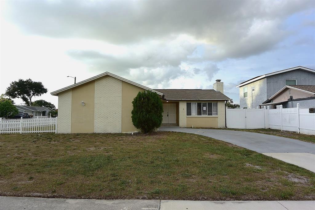 A single-story house with a beige brick facade, a concrete driveway, and a white fence — 8235 DONALDSON DRIVE, TAMPA, FL
