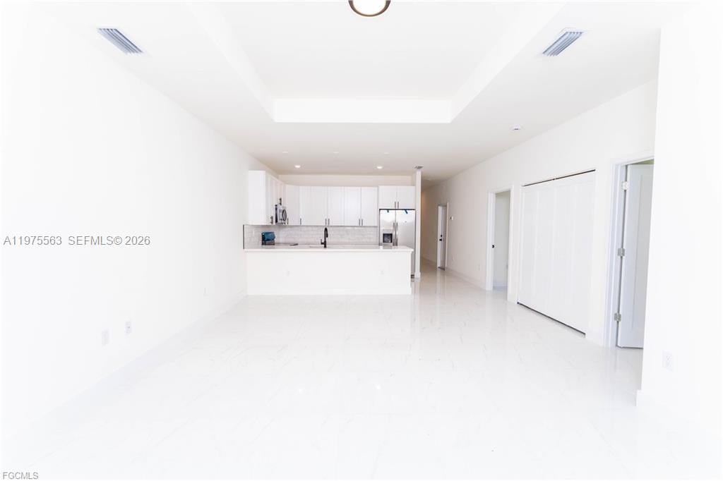 A bright, open-concept kitchen features white cabinetry, a breakfast bar, and glossy tile flooring — 4706 27th st sw, Lehigh Acres FL 33973, LEHIGH ACRES, FL
