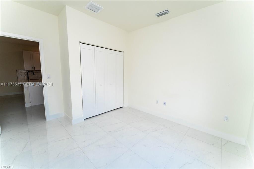 A room with white walls, white tile flooring, and a white bi-fold closet door — 4706 27th st sw, Lehigh Acres FL 33973, LEHIGH ACRES, FL