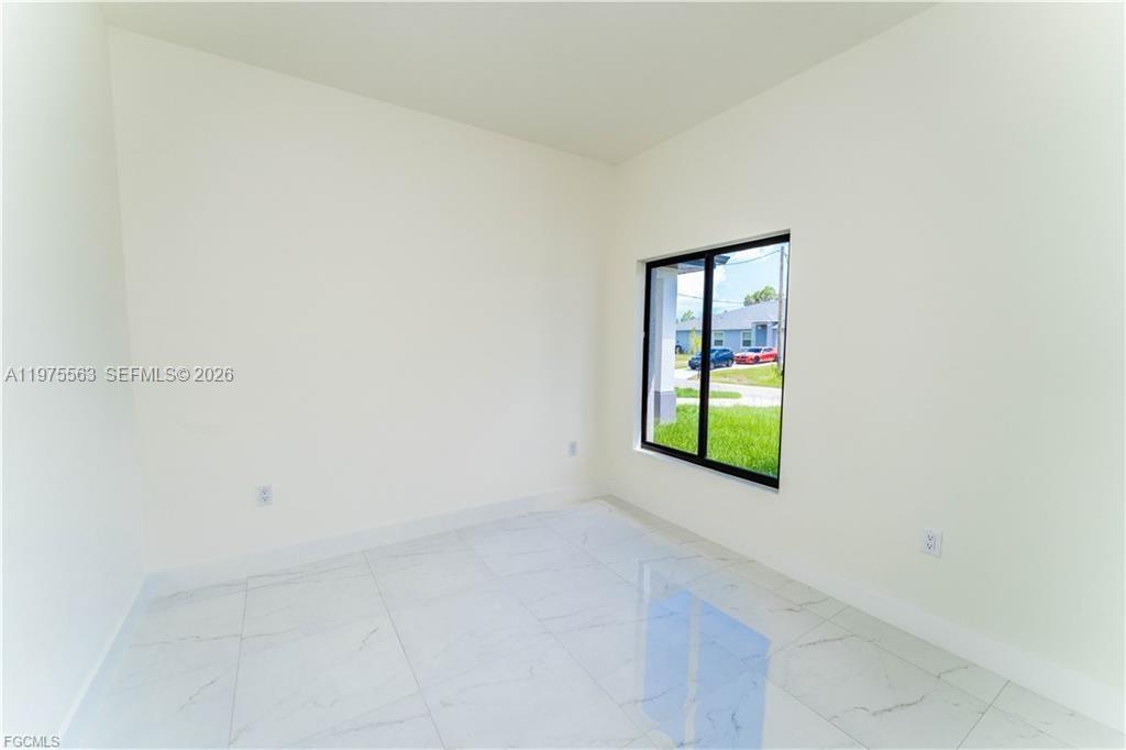 An empty room features white walls, marble-look tile flooring, and a large window — 4706 27th st sw, Lehigh Acres FL 33973, LEHIGH ACRES, FL