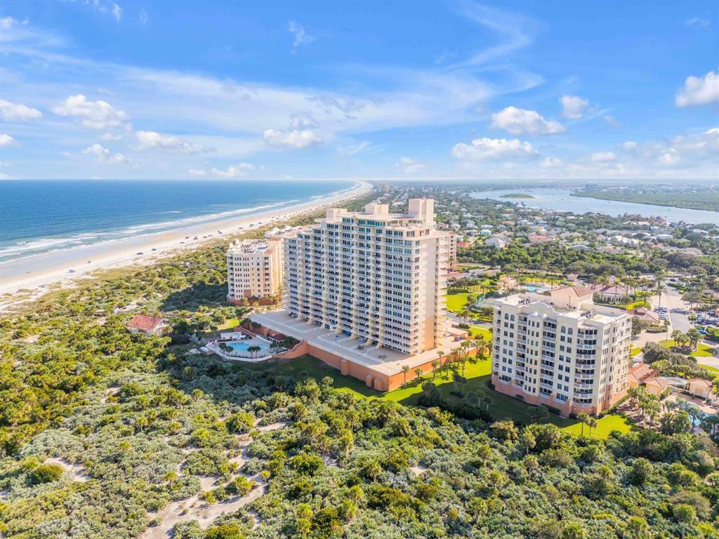 An aerial view shows three large residential buildings situated along a sandy beach and coastline — 257 MINORCA BEACH WAY UNIT 506, NEW SMYRNA BEACH, FL
