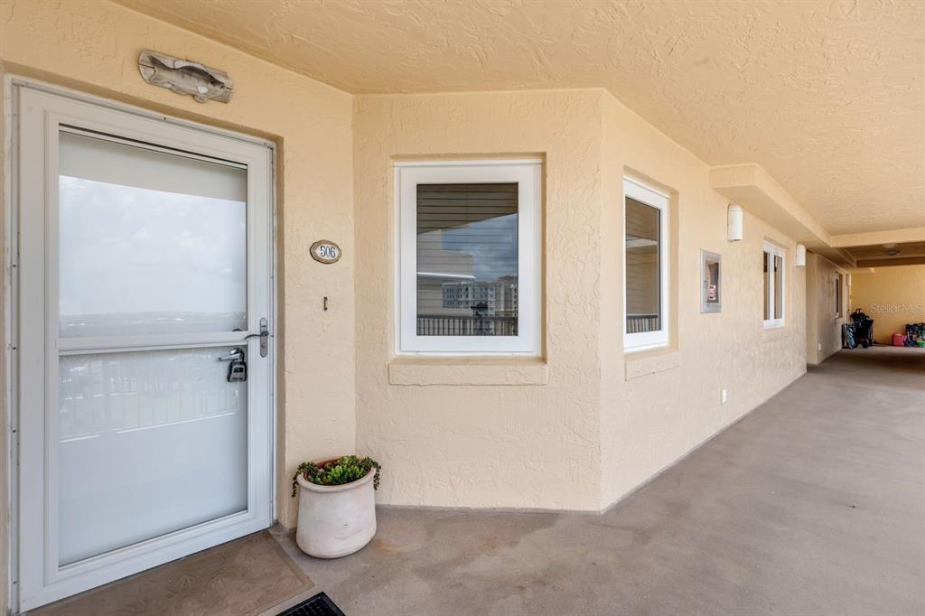 An exterior view of a building hallway featuring a door labeled 506 and windows — 257 MINORCA BEACH WAY UNIT 506, NEW SMYRNA BEACH, FL