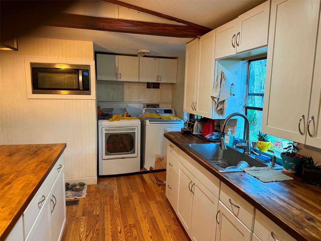 A kitchen with white cabinets, wood countertops, and a laundry area with white appliances — 186 GLADYS AVENUE, INGLIS, FL