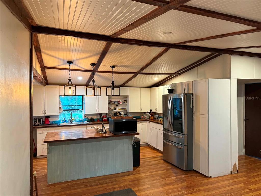 A kitchen features white cabinets, a wood-topped island, stainless steel appliances, and a vaulted ceiling — 186 GLADYS AVENUE, INGLIS, FL