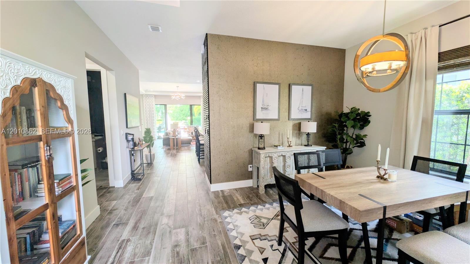 A dining area features a wooden table, a textured accent wall, and a wood-framed cabinet — 2879 Gin Berry Way, West Palm Beach FL 33401, WEST PALM BEACH, FL