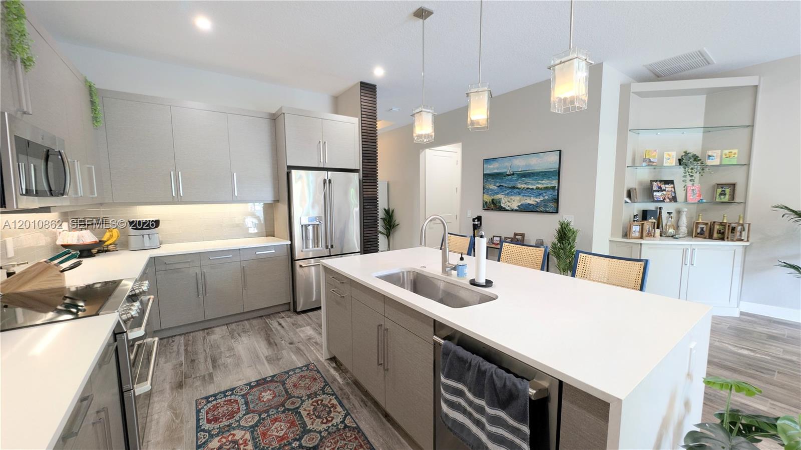 A modern kitchen features gray cabinetry, a white island with a sink, and stainless appliances — 2879 Gin Berry Way, West Palm Beach FL 33401, WEST PALM BEACH, FL