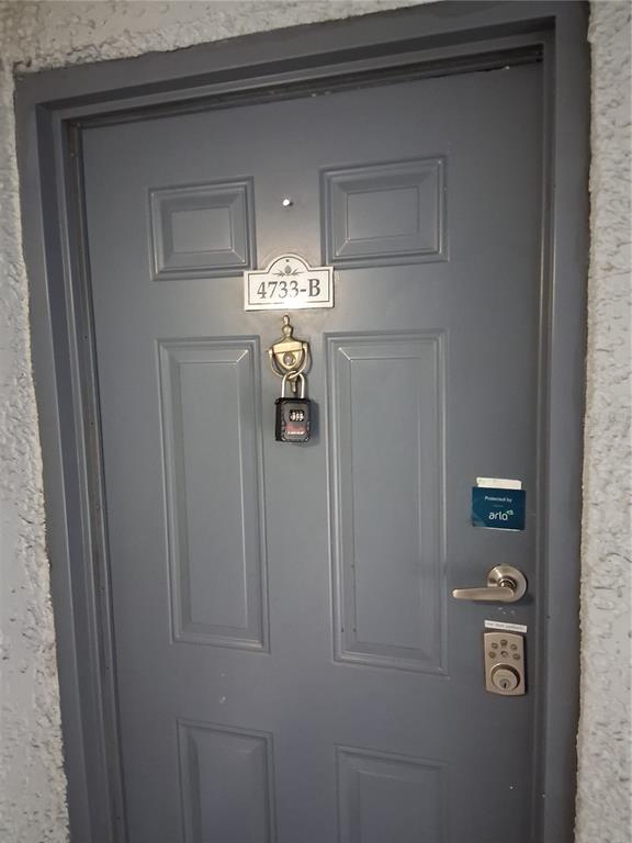 A gray door features a brass knocker, a combination lockbox, and a digital keypad lock — 4733 S TEXAS AVENUE UNIT 4733B, ORLANDO, FL