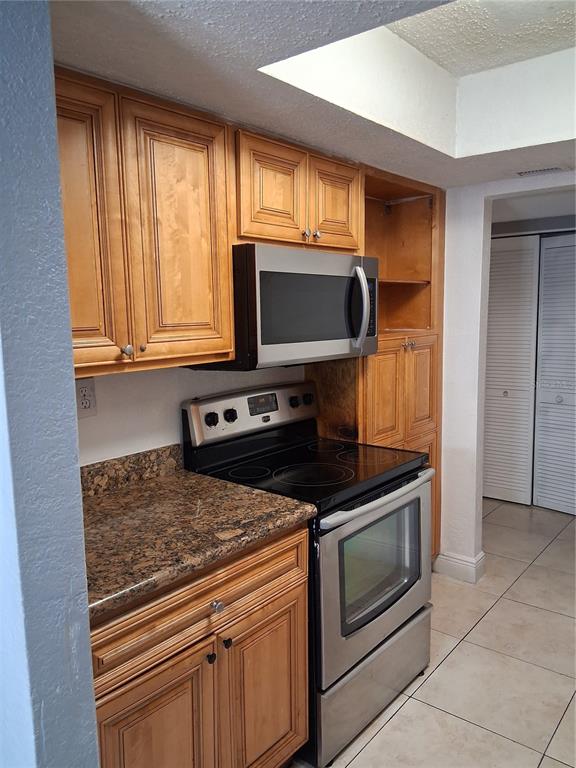 A kitchen features wood cabinets, stainless steel appliances, and granite countertops — 4733 S TEXAS AVENUE UNIT 4733B, ORLANDO, FL