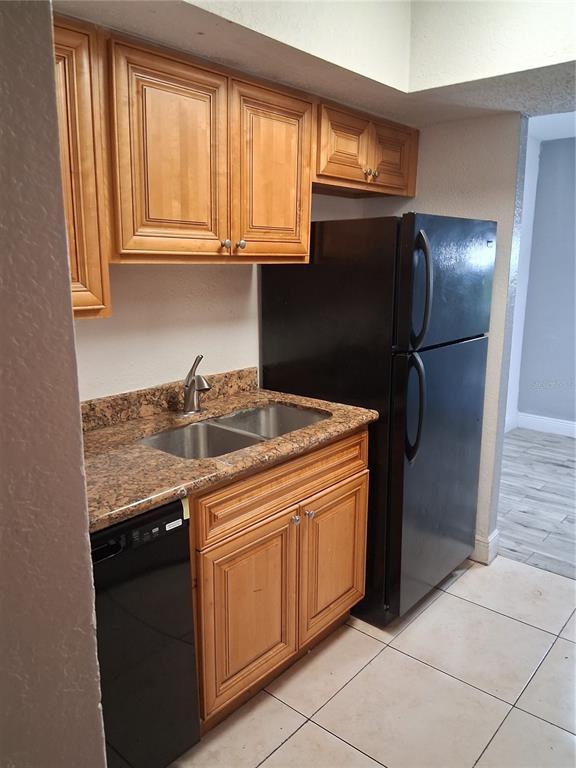 A kitchen features wood cabinets, granite countertops, a double sink, and black appliances — 4733 S TEXAS AVENUE UNIT 4733B, ORLANDO, FL