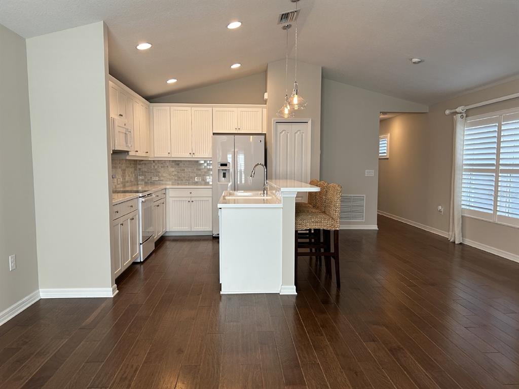 A kitchen with white cabinets, stainless steel appliances, and a breakfast bar on wood floors — 12721 SAGEWOOD DRIVE, VENICE, FL