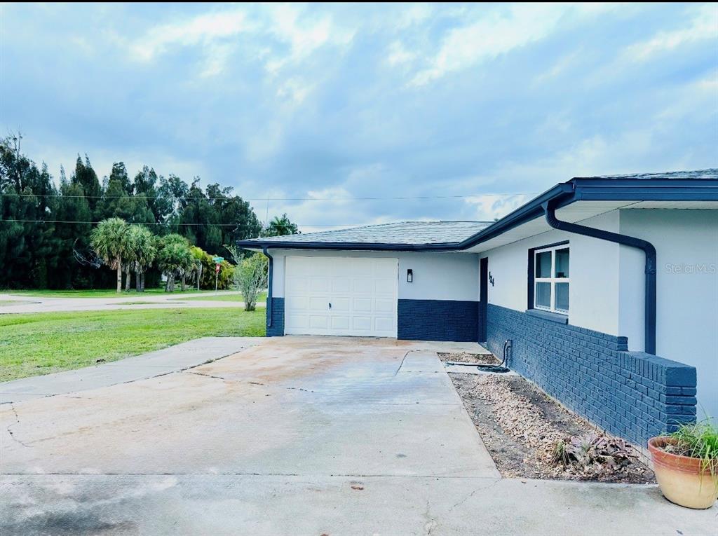 A single-story house exterior features a white garage door, gray siding, and a concrete driveway — 134 PEACE ISLAND DRIVE, PUNTA GORDA, FL