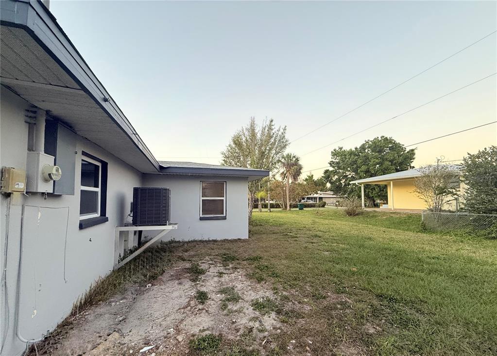 The exterior of a light gray house features an air conditioning unit and a yard — 134 PEACE ISLAND DRIVE, PUNTA GORDA, FL