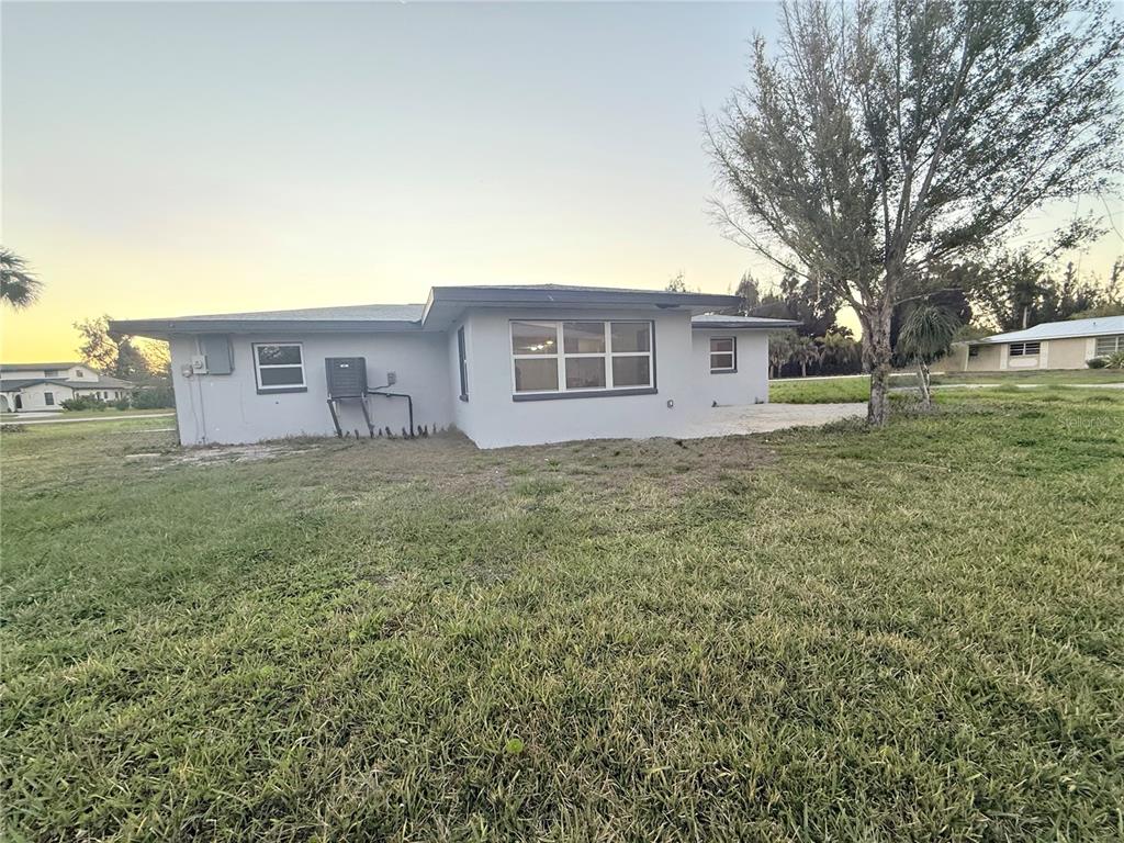 A single-story house with a gray exterior, a large window, and a grassy backyard — 134 PEACE ISLAND DRIVE, PUNTA GORDA, FL