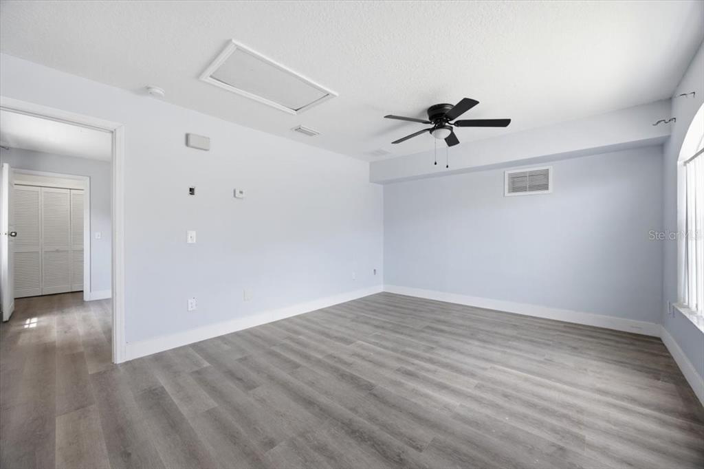 An empty bedroom features light blue walls, wood-look flooring, a ceiling fan, and a closet — 713 WASHINGTON PALM LOOP Front Unit, DAVENPORT, FL