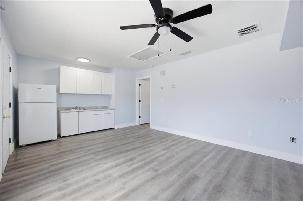 A room with light blue walls, gray wood-look flooring, a ceiling fan, and a kitchenette — 713 WASHINGTON PALM LOOP Front Unit, DAVENPORT, FL
