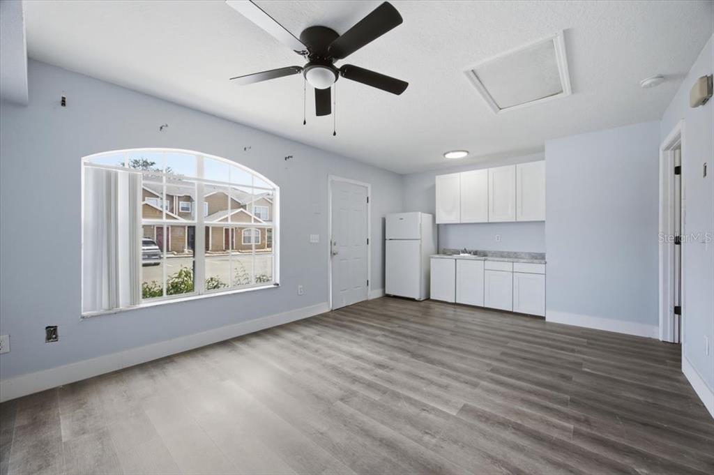 A room with light blue walls, wood-look flooring, a ceiling fan, and a small kitchenette — 713 WASHINGTON PALM LOOP Front Unit, DAVENPORT, FL