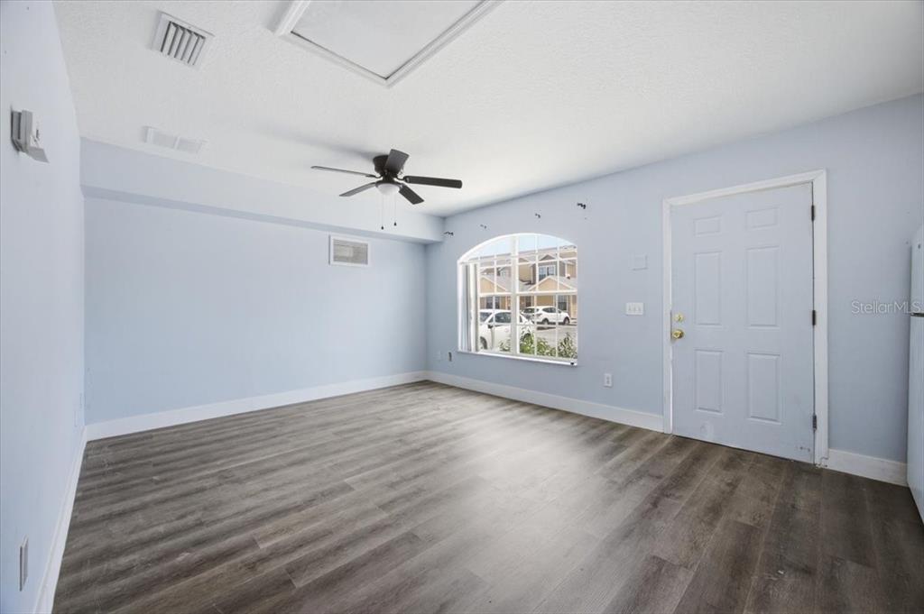 An empty room with light blue walls, wood-look flooring, a ceiling fan, and a window — 713 WASHINGTON PALM LOOP Front Unit, DAVENPORT, FL