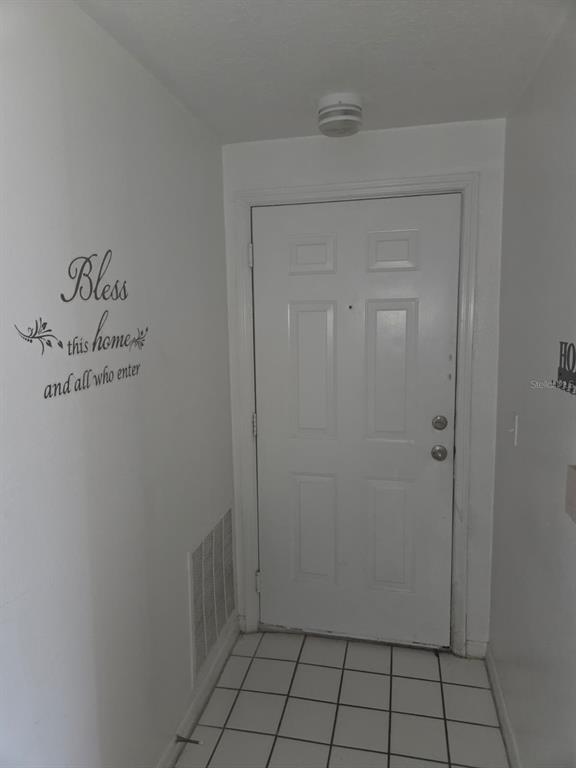 An entryway features a white door, tiled floor, and a wall decal — 5566 METROWEST BOULEVARD UNIT 2-205, ORLANDO, FL