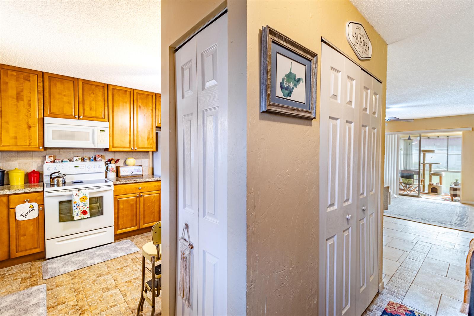 A kitchen with wood cabinets and white appliances sits beside a hallway with closet doors — 849 Salem Lane, Lake Worth FL 33467, LAKE WORTH, FL