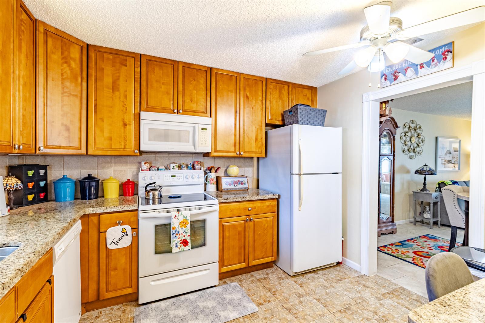 A kitchen features wood cabinets, granite countertops, white appliances, and a ceiling fan — 849 Salem Lane, Lake Worth FL 33467, LAKE WORTH, FL