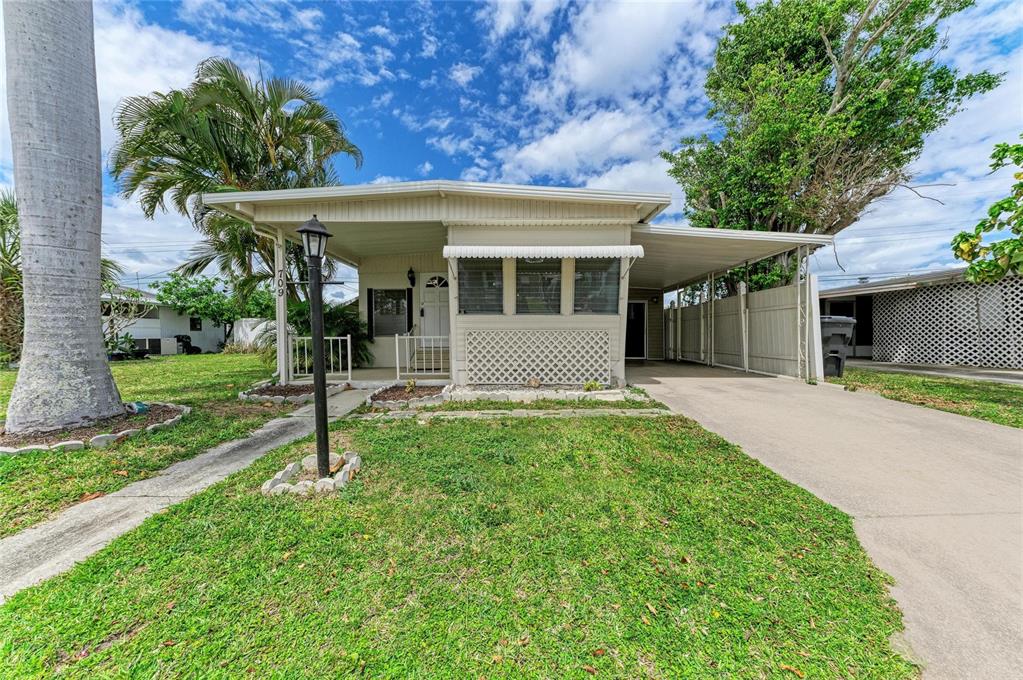 A single-story mobile home features a carport, a front porch, and a grassy lawn — 709 50TH AVENUE TERRACE W, BRADENTON, FL