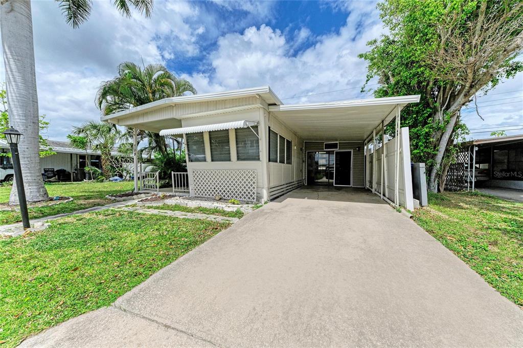 A single-story manufactured home with a concrete driveway, carport, and a small front porch — 709 50TH AVENUE TERRACE W, BRADENTON, FL