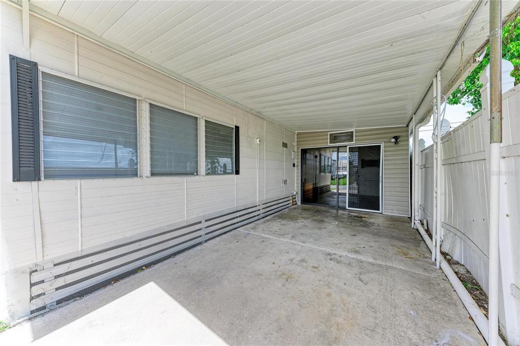 A concrete carport area features a sliding glass door and horizontal siding exterior walls — 709 50TH AVENUE TERRACE W, BRADENTON, FL
