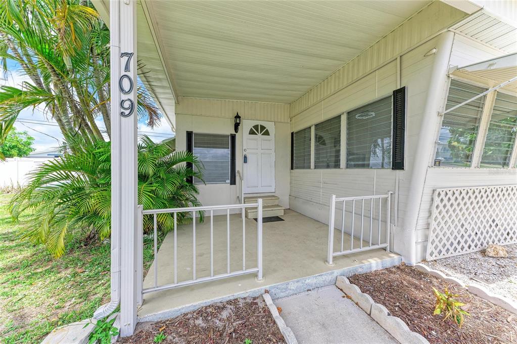 A covered porch with a white railing leads to the front door of a home — 709 50TH AVENUE TERRACE W, BRADENTON, FL