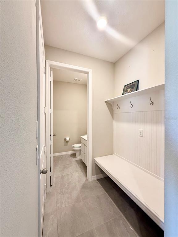 A mudroom with a built-in bench and coat hooks leads into a small bathroom — 30877 QUAIL CAPER CIRCLE, SAN ANTONIO, FL