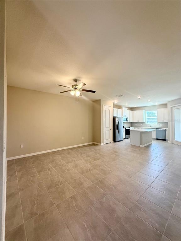 An open-concept kitchen and dining area features tile flooring, white cabinetry, and a ceiling fan — 30877 QUAIL CAPER CIRCLE, SAN ANTONIO, FL