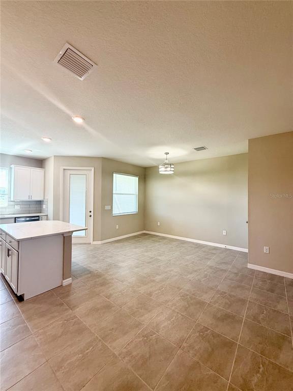 A kitchen with white cabinets and an island opens into a tiled dining area — 30877 QUAIL CAPER CIRCLE, SAN ANTONIO, FL