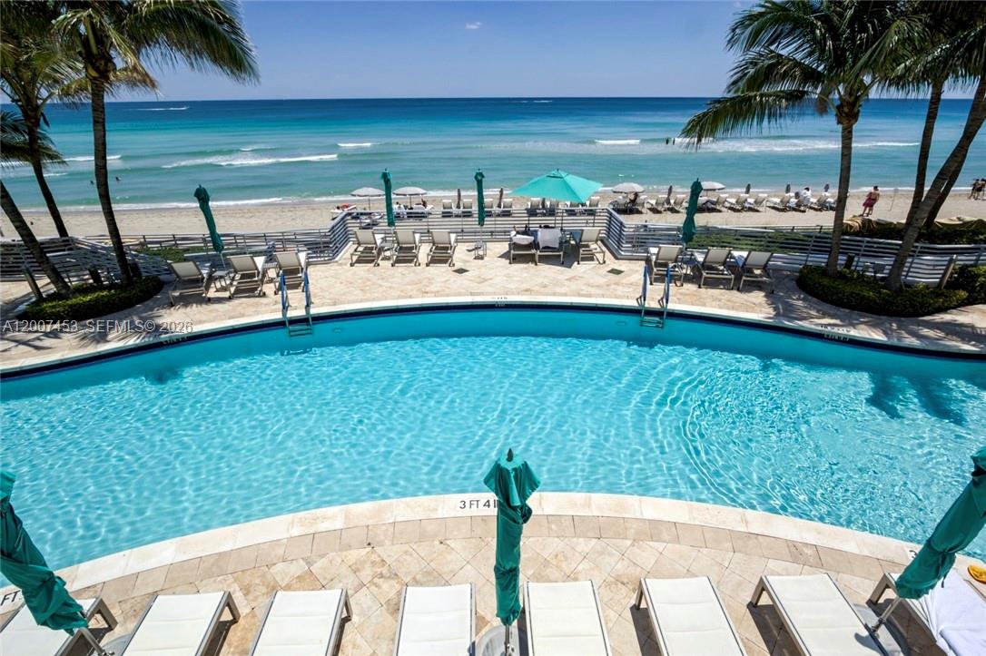A swimming pool overlooks a sandy beach and the ocean from a paved patio — 3535 S OCEAN DR # 2002, Hollywood FL 33019, HOLLYWOOD, FL