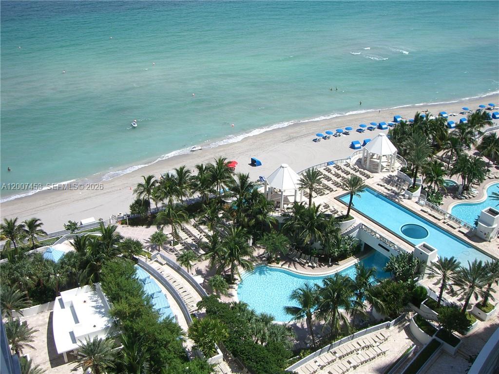 An aerial view shows a resort pool area next to a sandy beach and ocean — 3535 S OCEAN DR # 2002, Hollywood FL 33019, HOLLYWOOD, FL