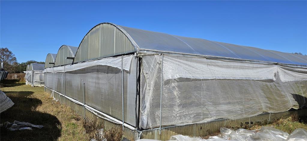 A row of arched greenhouses with plastic siding stands in a grassy field — 3557 KOKOMO ROAD, HAINES CITY, FL