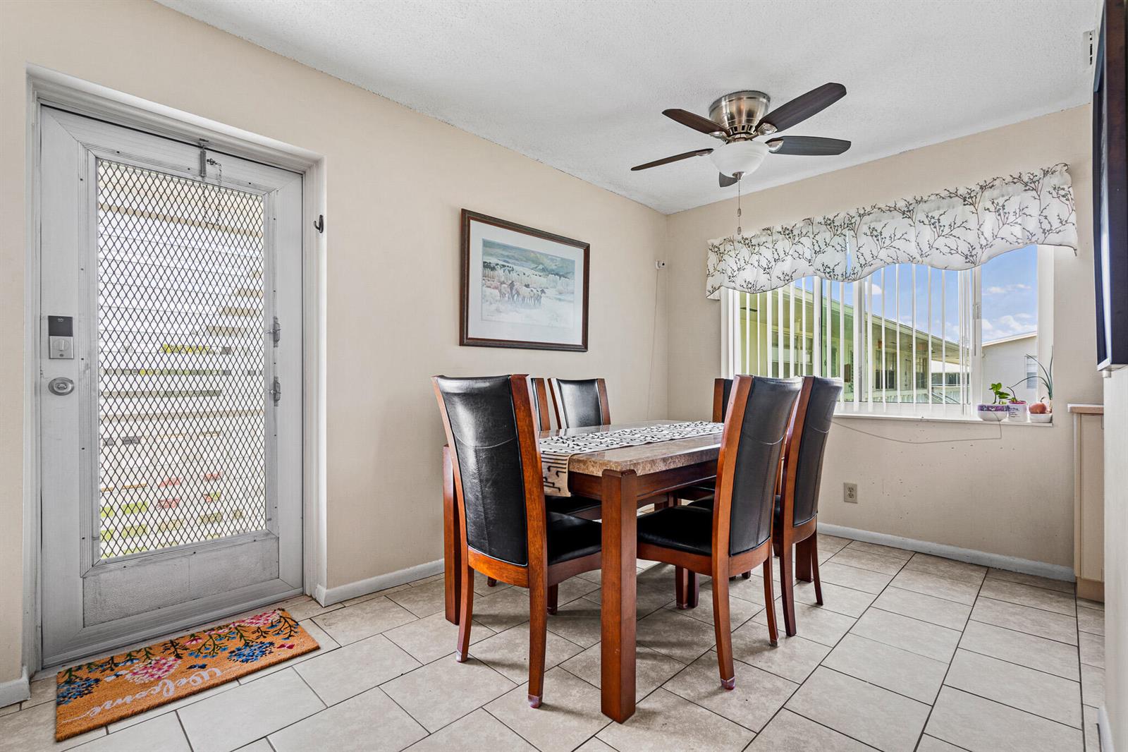 A dining area features a wooden table with black chairs, tile flooring, and a ceiling fan — 167 Cambridge G, West Palm Beach FL 33417, WEST PALM BEACH, FL