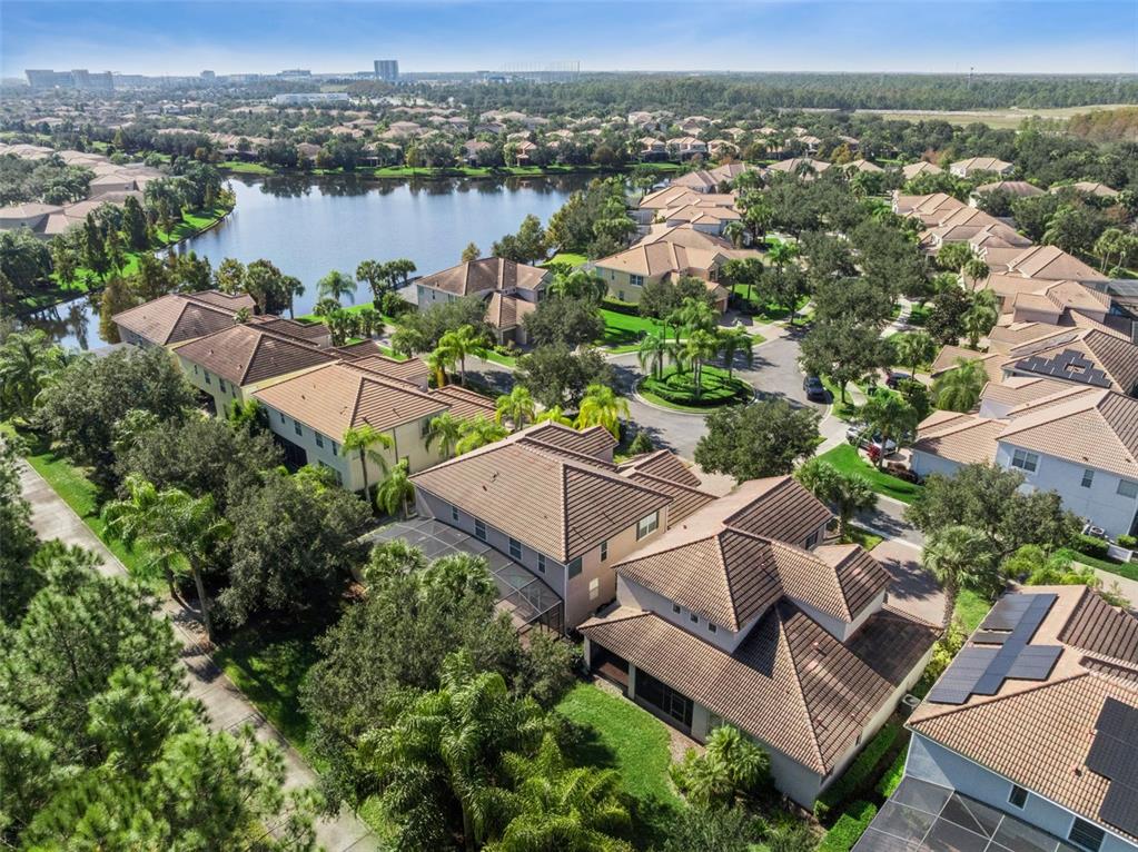 An aerial view shows a residential neighborhood with houses, a lake, and palm trees — 7991 ESTA LANE, ORLANDO, FL