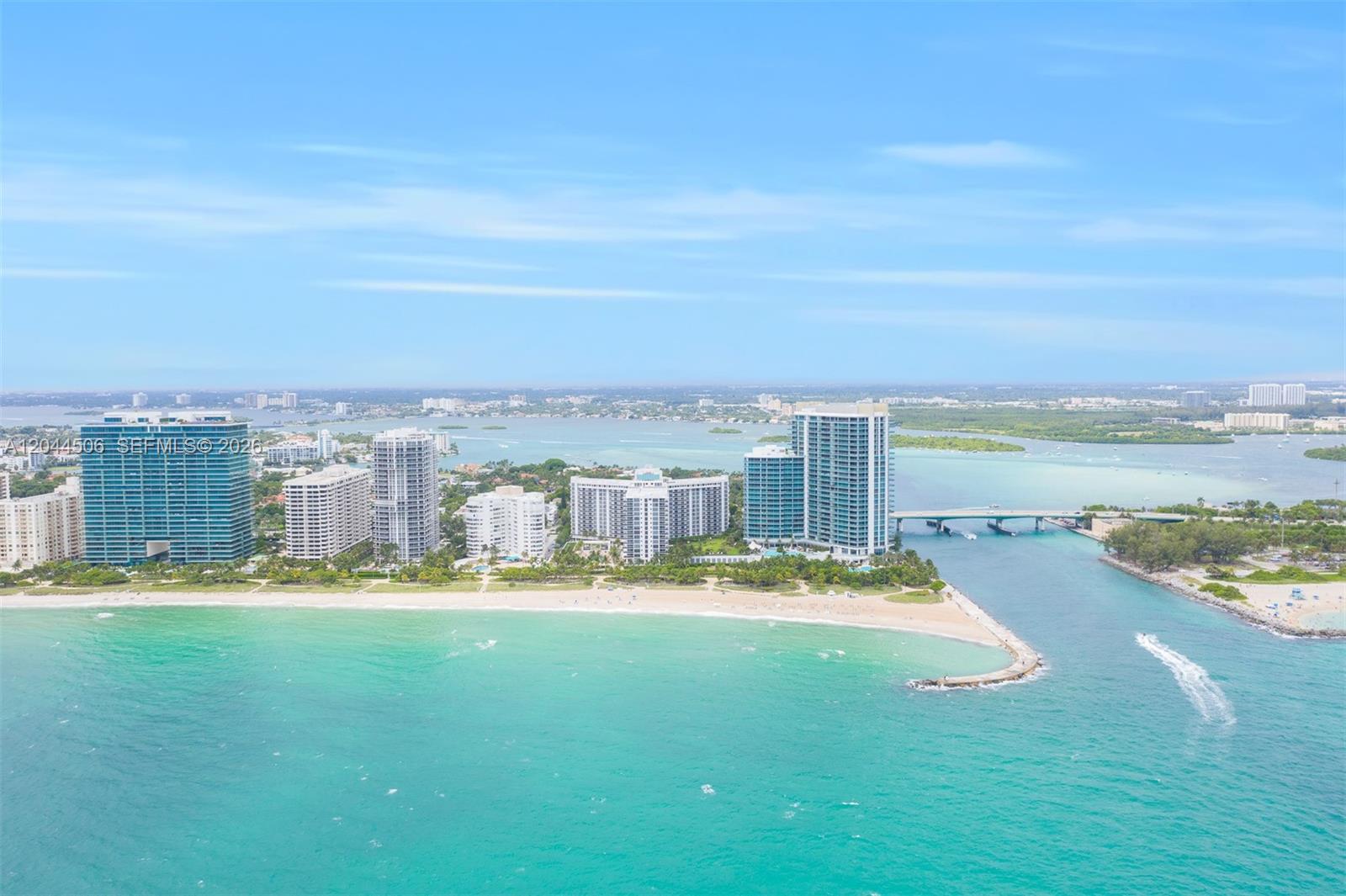 An aerial view shows a sandy beach, turquoise ocean, and several high-rise buildings near a bridge — 10275 E Collins Ave # 502, Bal Harbour FL 33154, BAL HARBOUR, FL
