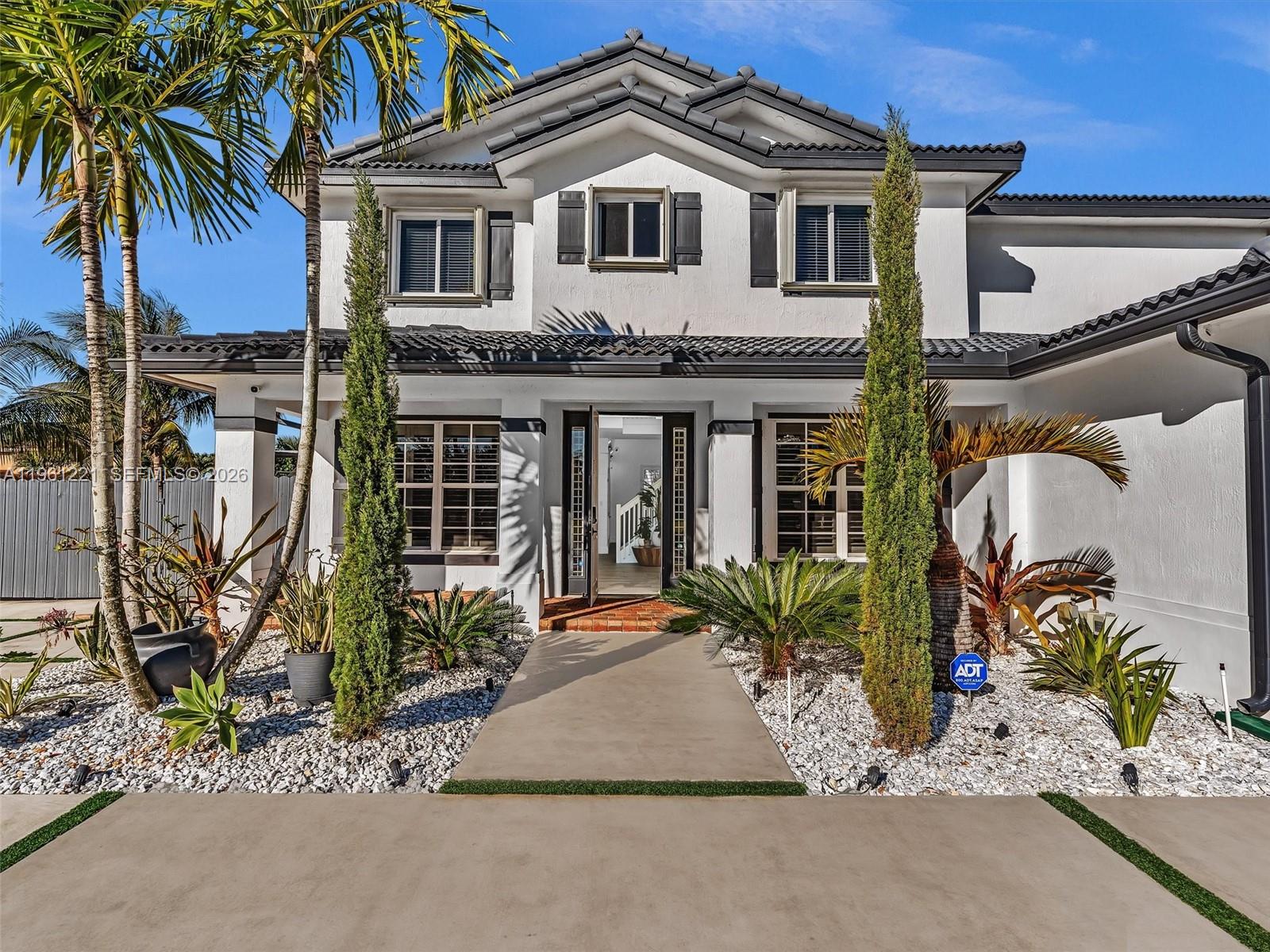 A two-story white house with a tiled roof, palm trees, and a concrete walkway entrance — 22690 SW 127th Ct, Miami FL 33170, MIAMI, FL